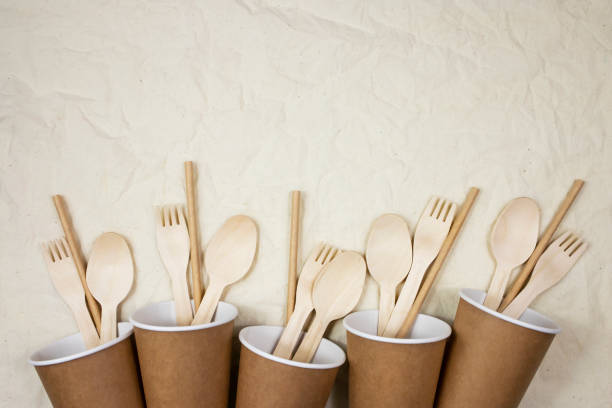 istock Plastic free concept. Disposable bamboo cutlery in disposable paper cups on canvas background. 1302317419