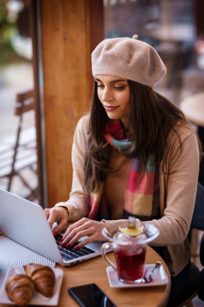 istock Attractive young woman using her laptop while sitting at table in the cafe 1302318208