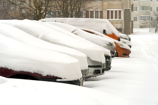 Snow-covered cars in the parking lot on a winter day