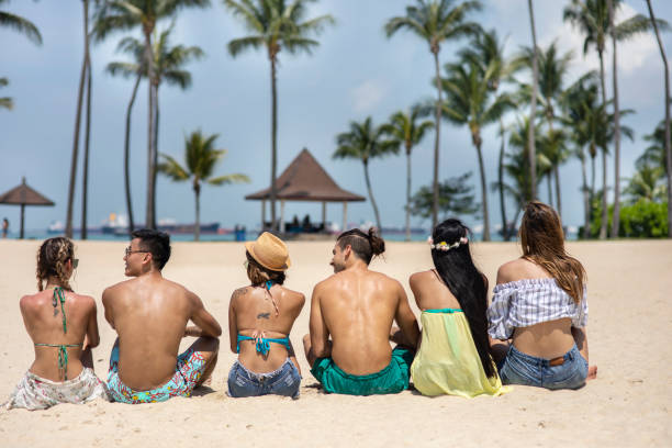 istock Group of friends sitting on beach 1302319377