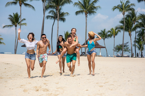 Couples having fun on beach, piggyback ride.