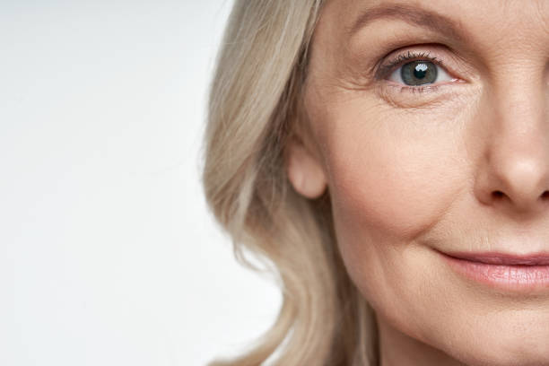 50s middle aged old woman looking at camera isolated on white background advertising dry skin care treatment anti age skincare beauty, plastic surgery, cosmetology procedures. close up half face view - wrinkles eyes imagens e fotografias de stock