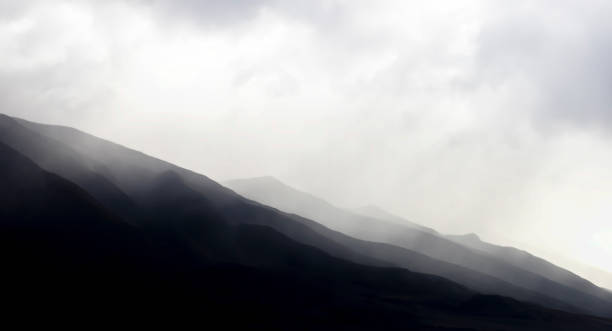 Monochromatic Mountain Ridges Under Morning Cloud Mist stock photo