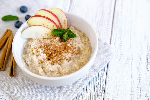 Delicious oatmeal with apple and cinnamon. Fresh natural breakfast served on wooden table