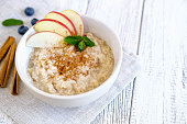 Delicious porridge with apple and cinnamon. Fresh natural breakfast served on wooden table