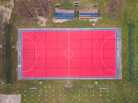 Aerial view of a red handball field. Outdoor sport ground with red surface for playing handball,  lamps and benches for spectators Winter shot
