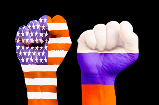 Two fists with embedded American and Russian flag on black background to represent conflict between the two countries or enthusiasm in politics relations