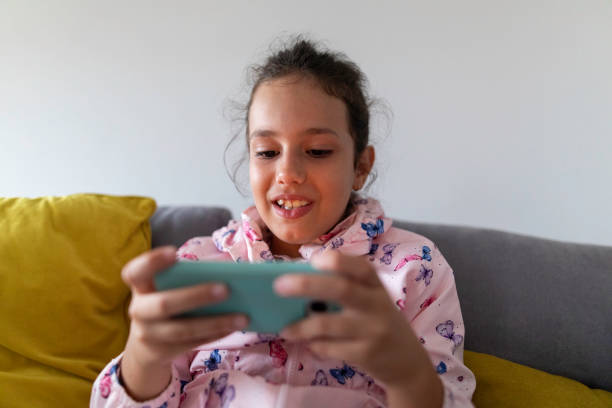 istock Girl having fun playing mobile game while sitting on sofa at home 1302330717