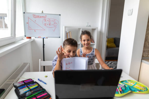 istock Brother and sister attending online school class using laptop from home 1302330843