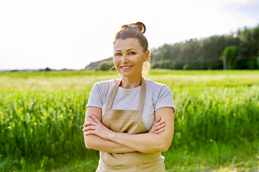 Portrait of mature smiling woman farmer in field.