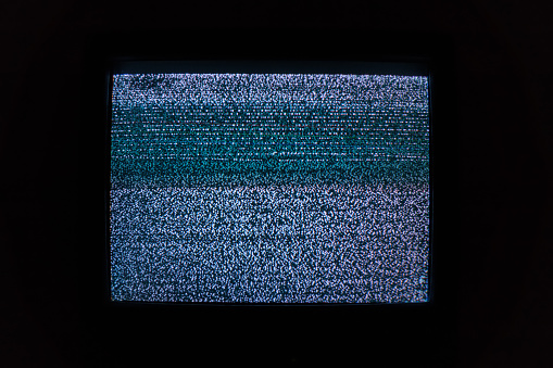 Old TV screen with noisy image due to lack of TV signal in dark room
