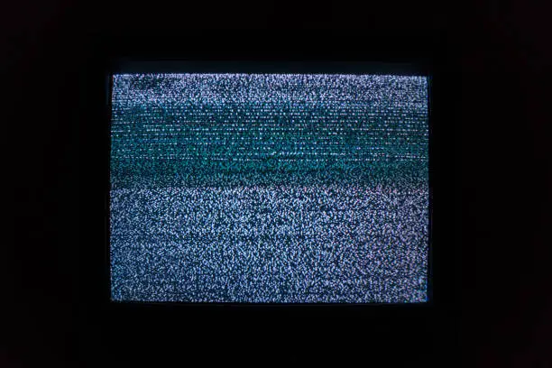 Old TV screen with noisy image due to lack of TV signal in dark room