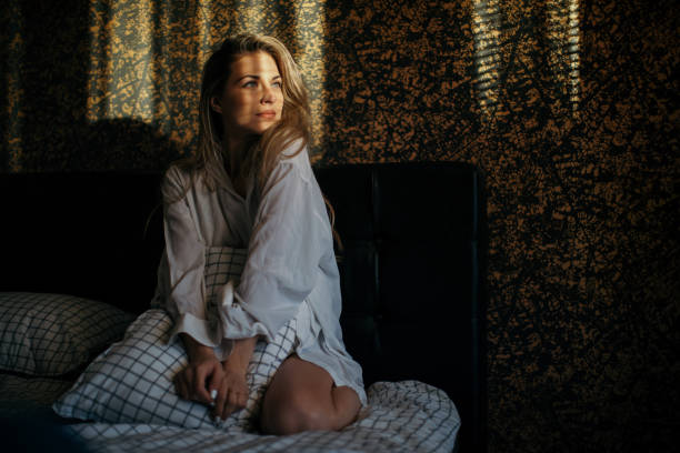 istock Young woman enjoying first morning sunlight in her bedsheets 1302333535