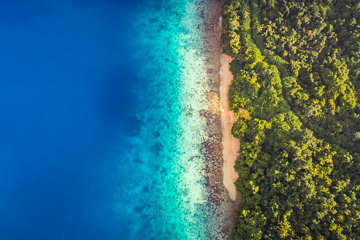 Aerial view of calm aqua marine blue water with tropical secluded beach