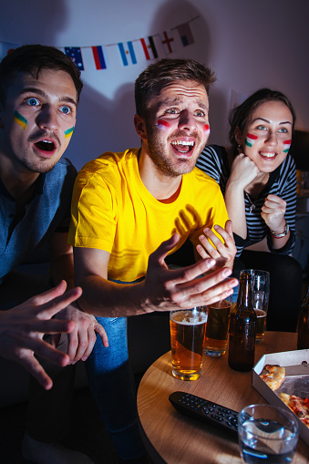 Group of sport fans watching a game together at home