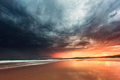 istock Tidal retreat reflecting dramatic storm on the beach at sunset 1302339961