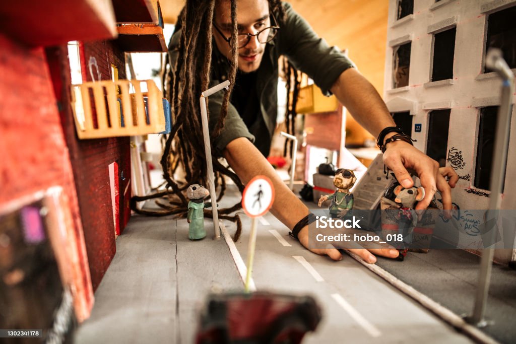 Process of making stop motion animation Stop motion artist sculpting characters and preparing city model set, ready for filming his stop motion animation in his home art studio Movie Stock Photo Process of making stop motion animation Stop motion artist sculpting characters and preparing city model set, ready for filming his stop motion animation in his home art studio Movie Stock Photo