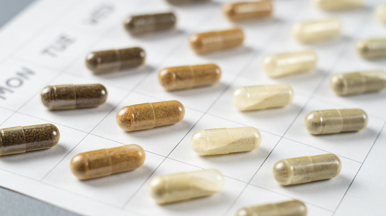 Medicines or dietary supplements in capsules on a calendar sheet. Pill schedule