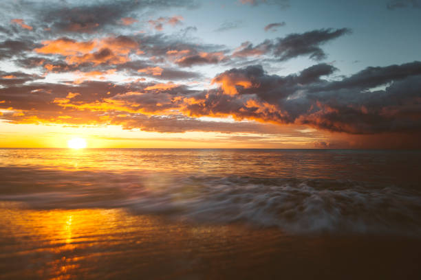 Waves and tidal movement with dramatic storm on the beach at sunset