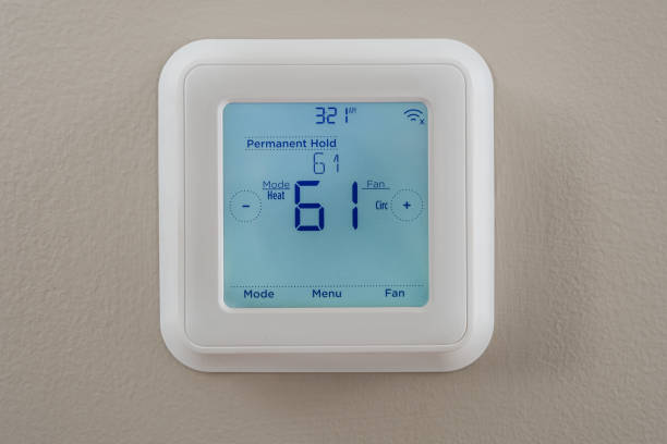 Programmable Heating and Cooling Thermostat Photograph of a modern residential programmable heating and cooling thermostat mounted on a wall smart thermostat stock pictures, royalty-free photos & images