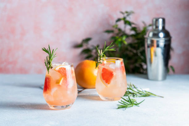 tequila cocktail or cold lemonade with grapefruit juice, tinted with the aroma of a fresh sprig of rosemary - grapefruit fruit freshness pink imagens e fotografias de stock
