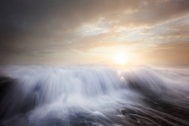 Ocean waves flowing over rocks at sunrise with dramatic sky