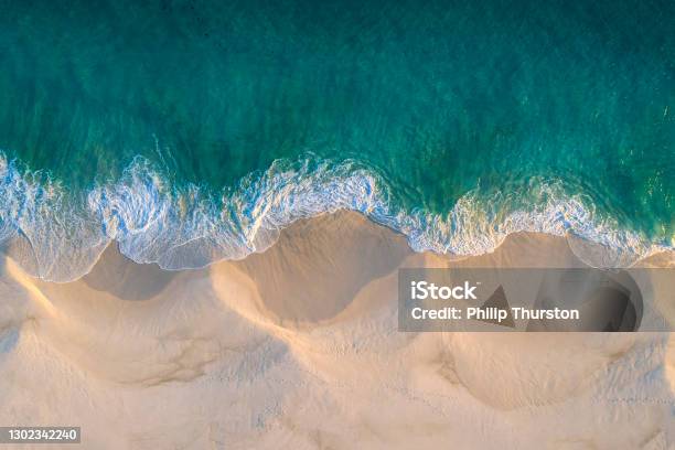 Aerial View Of White Sand Beach Coastline And Swirling Waves With Teal Blue Ocean Stock Photo - Download Image Now
