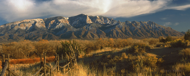 This is a north view of the Sandia Mountains in autumn. The mountain peaks have a fresh dusting of snow. The Sandia Mountains, are a mountain range immediately east of the the city of Albuquerque in New Mexico. The are a part of the Sandia-Manzano Mountains.