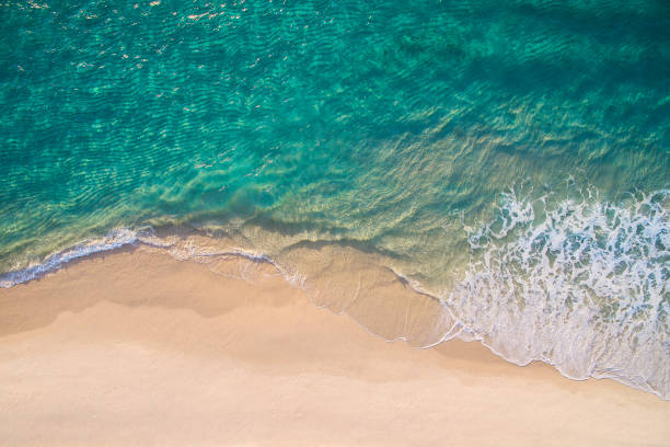 saubere meereswellen brechen auf weißem sandstrand mit türkis smaragdfarbenem wasser - beach stock-fotos und bilder