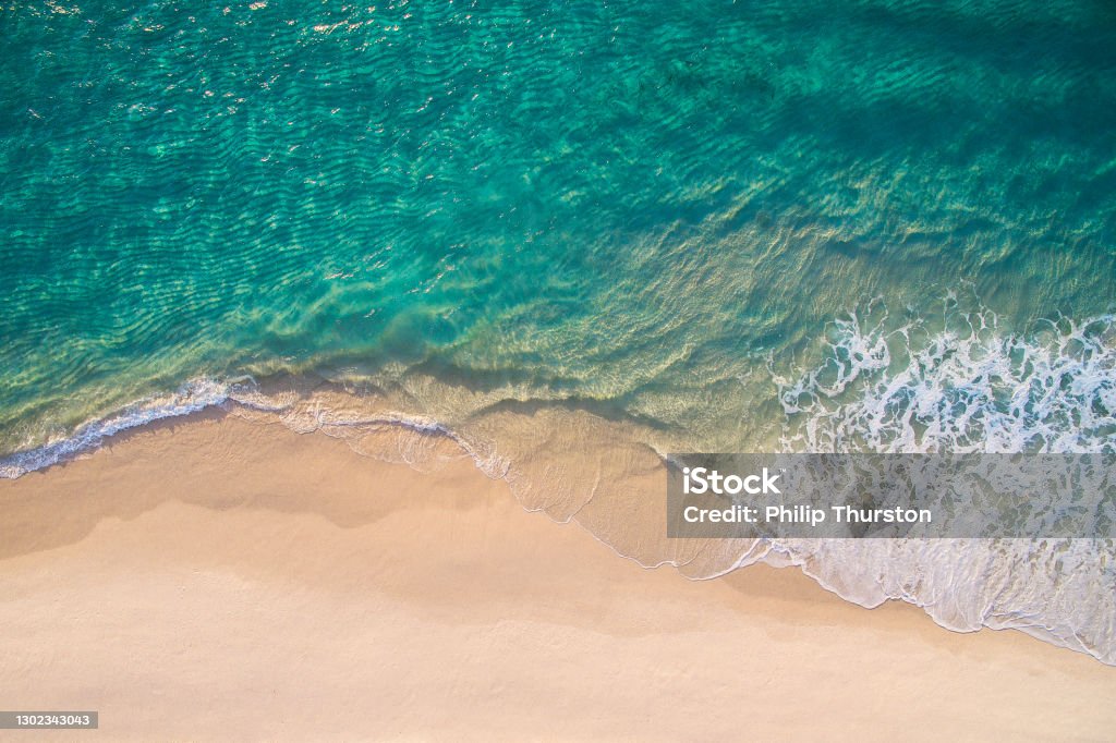Clean ocean waves breaking on white sand beach with turquoise emerald coloured water Clean ocean waves breaking on white sand beach with turquoise emerald coloured water. Aerial view. Perfect weather. Beach Stock Photo