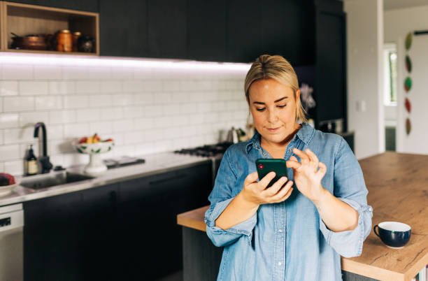 istock Woman in Kitchen with Smart phone and coffee cup 1302347994