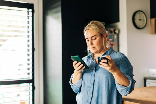 istock Woman in Kitchen with Smart phone and coffee cup 1302348002