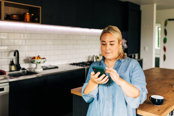 istock Woman in Kitchen with Smart phone and coffee cup 1302348018