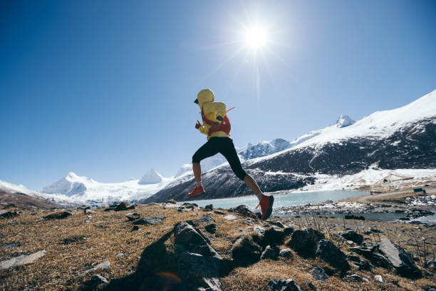 冬の山々で走る女性トレイルランナークロスカントリー - exploration mountain ice jumping ストックフォトと画像