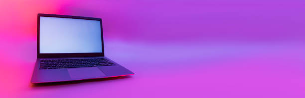 istock Slim modern laptop with white screen on the background creative light. Mockup in colorful bright neon UV blue and purple lights. 1302350816