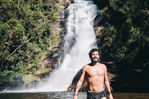 Man at waterfall.\nSanto Isidro waterfall at Serra da Bocaina National Park.