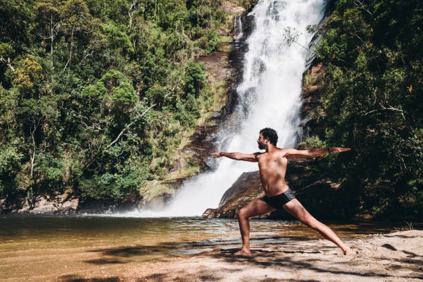 istock Man doing yoga exercise in front of a waterfall 1302351623