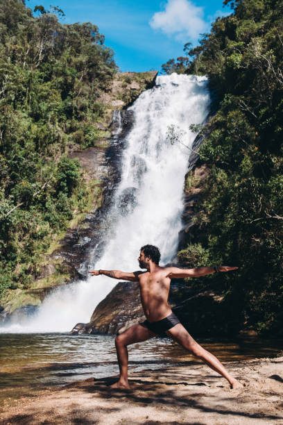 istock Man doing yoga exercise in front of a waterfall 1302351785