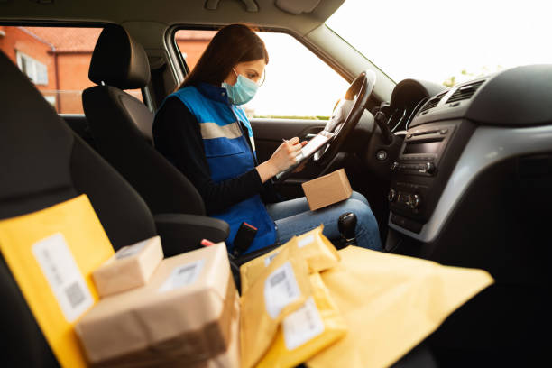 istock Young female courier in a van using a digital tablet before delivery and checking packages during the epidemic 1302351844
