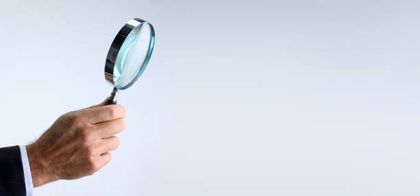 istock Man Holding Magnifying Glass 1302351871