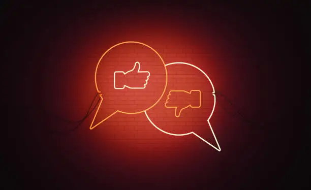Photo of White and Red Neon Speech Bubble Pair Thumbs Up and Thumbs Down Arrow Symbols Sitting Over Black Wall