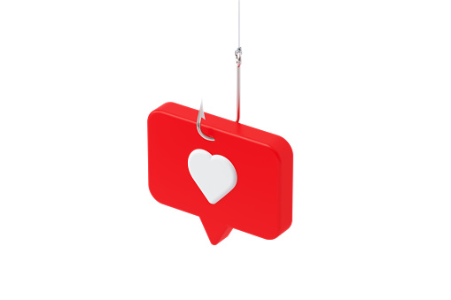 Red speech bubble with white heart shape hooked by a fishing hook on white background. Horizontal composition with copy space. Online dating and messaging security and scam concept.