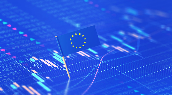 EU flag sitting over blue financial chart. Horizontal composition with selective focus and copy space. Eurozone finance and stock market concept.