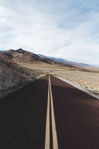 colpo verticale della strada desertica per la valle della morte, california - arid climate asphalt barren blue foto e immagini stock