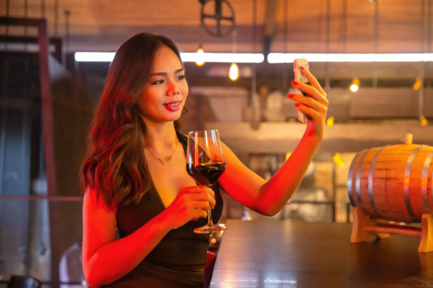 bellissimo influencer del sud-est asiatico che si fa selfie mentre assaggia il vino rosso - sensuality people mobile phone 30s foto e immagini stock