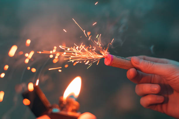 jeune homme allumant le pétard dans sa main - firework explosive material photos et images de collection