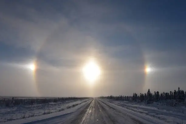 Ice crystals in the atmosphere reflect sunlight to form a halo around the sun. The two bright spots to the left and right of the sun are called sundogs.
