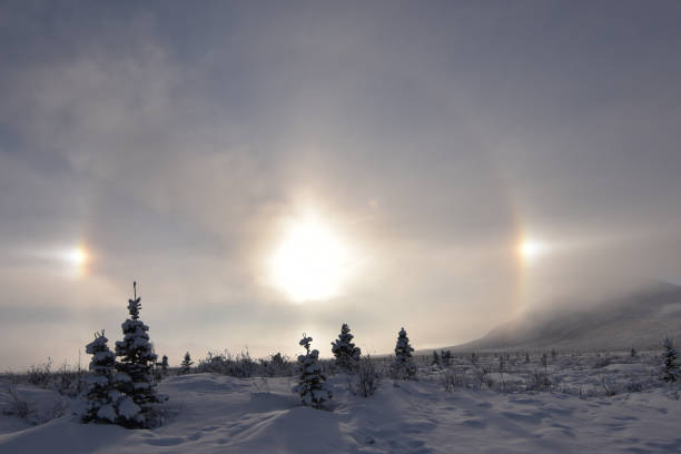 Ice crystals in the atmosphere reflect sunlight to form a halo around the sun. The two bright spots to the left and right of the sun are called sundogs.