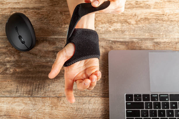 Chronic trauma to the wrist joint  in people using computer mouse Chronic trauma to the wrist joint  in people using computer mouse may lead to disorders that cause inflammation and pain. A woman working on desk uses wrist support brace and ergonomic vertical mouse carpal tunnel syndrome photos stock pictures, royalty-free photos & images