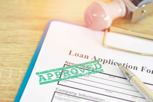 Aprobación de préstamos, formulario de solicitud de préstamo con estampación de caucho que dice aprobado por préstamos, crédito de contrato de préstamo financiero o persona. photo
